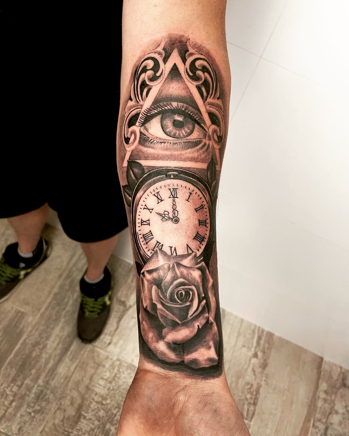 Antebrazo en negro y gris: ojo de la providencia, reloj de bolsillo y rosa